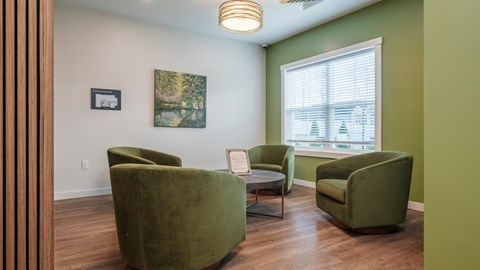A living room with green chairs and a painting on the wall.