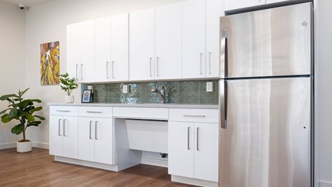 A kitchen with white cabinets and a refrigerator.