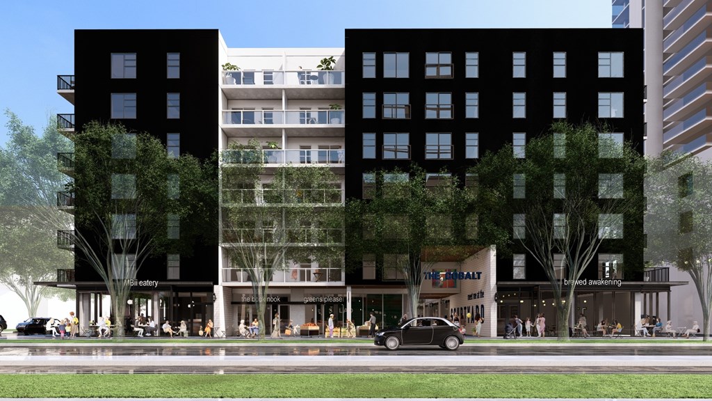 A black and white building with a car parked in front.