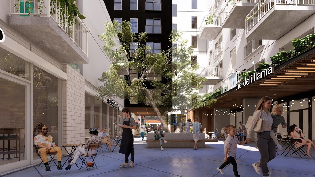 A group of people are walking through a courtyard with a tree in the middle.