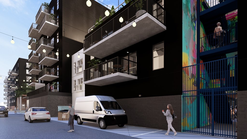 A street view of a building with a mural on the side and cars parked on the street.