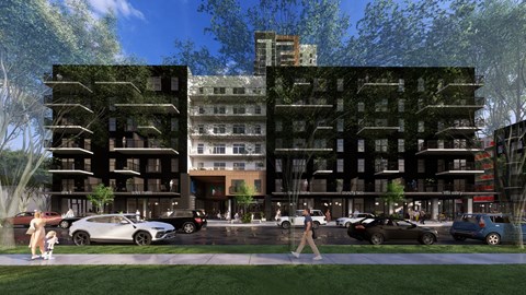 A modern building with a green wall on the side and cars parked in front.