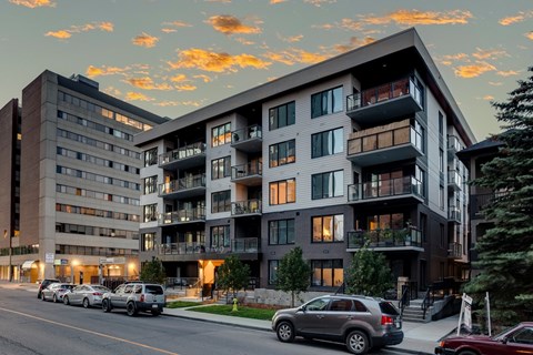 A modern apartment building with cars parked in front.