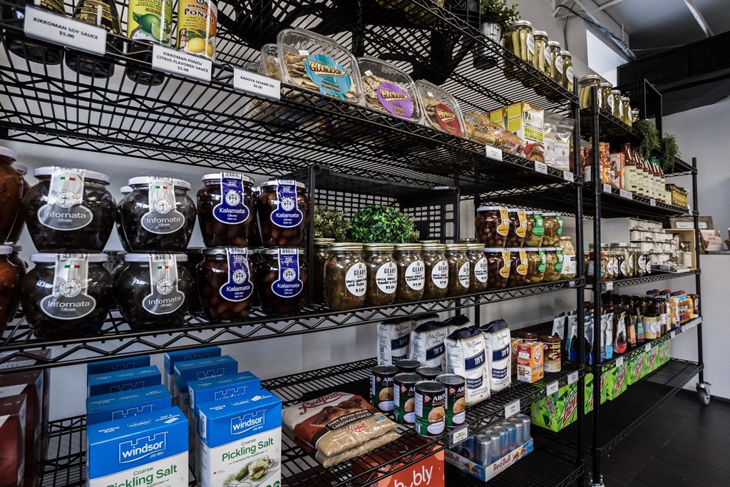A shelf of food products including jars of food and boxes of pickling salt.