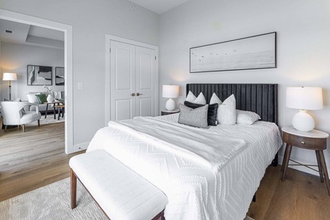 A bedroom with a large bed, a chair, and a painting on the wall.