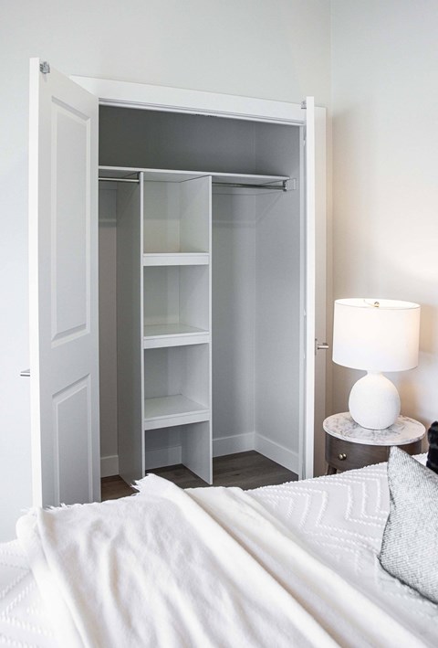 A white bedroom with a white bed and a white lamp.