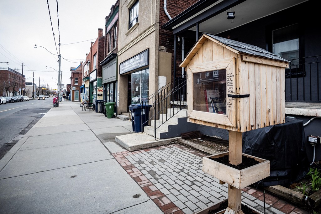 A wooden structure is in the middle of a brick sidewalk.