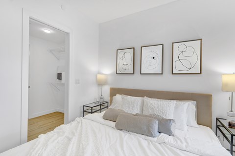 A bedroom with a large bed and three framed artworks on the wall.