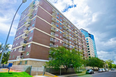 A tall apartment building with a blue sky and clouds in the background.