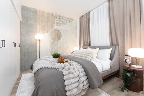 A bedroom with a large bed covered in a grey and white duvet.