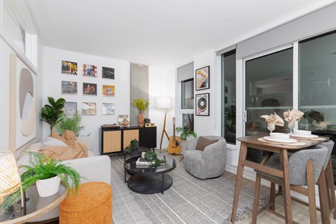 A living room with a grey couch, a coffee table, a guitar, and a dining table with chairs.