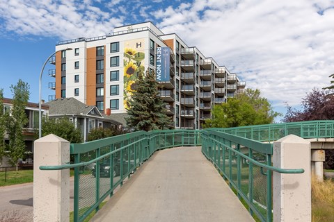 A bridge with a green railing leads to a building with a sign that says "Happy Now".