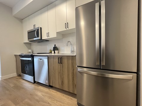 A modern kitchen with a stainless steel refrigerator and wooden cabinets.