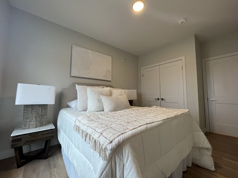 A bedroom with a large bed and a painting on the wall.