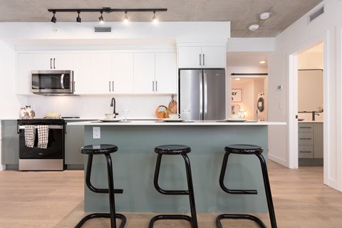 A kitchen with a blue counter and black stools.