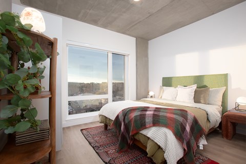 A bedroom with two beds and a balcony overlooking a cityscape.