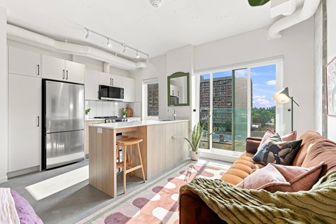 A modern kitchen with a refrigerator, microwave, and a bar area.