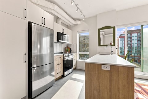 A modern kitchen with a wooden island and stainless steel appliances.
