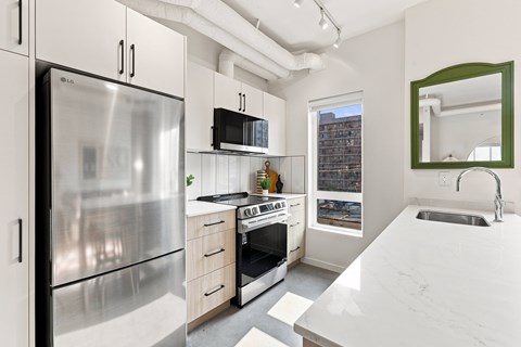 A modern kitchen with a stainless steel refrigerator and a marble countertop.