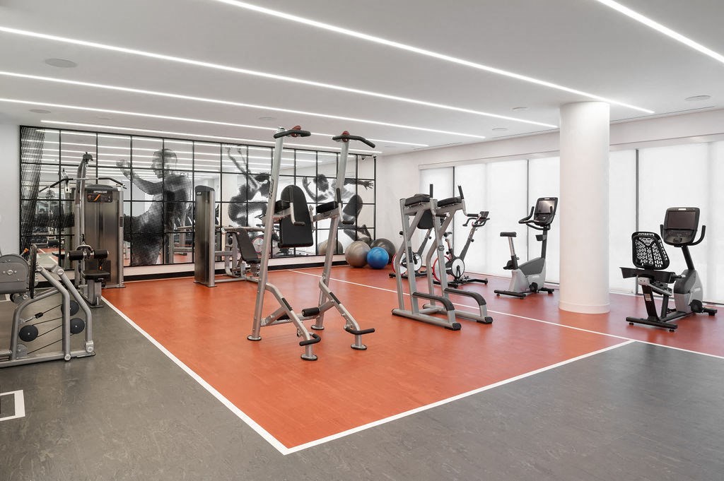 A gym with a variety of equipment including treadmills, weights, and exercise machines.