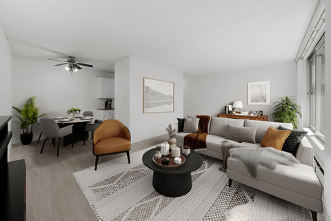 A modern living room with a grey sofa, a coffee table, and a dining table with chairs.