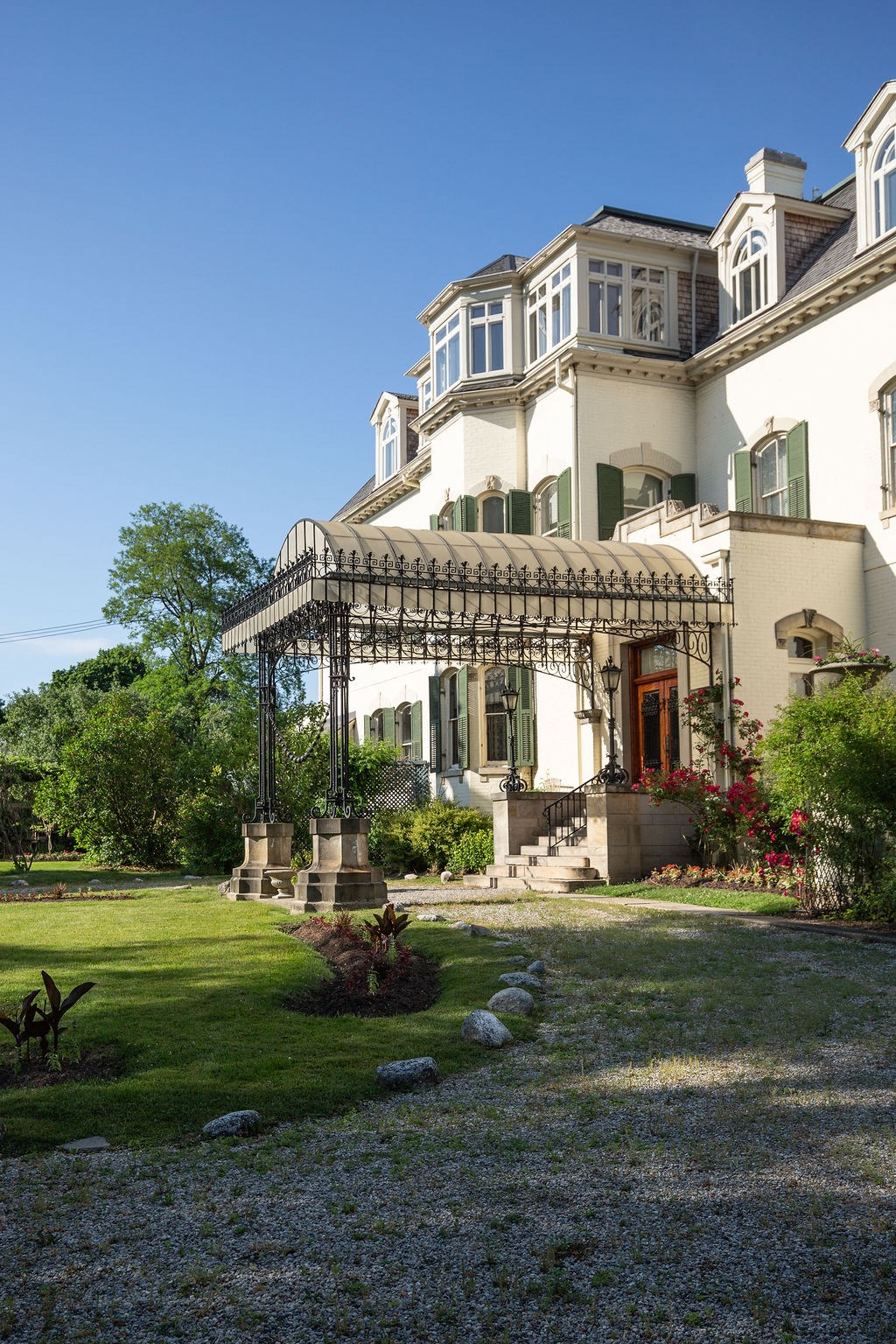A large white house with a balcony and a garden in front.