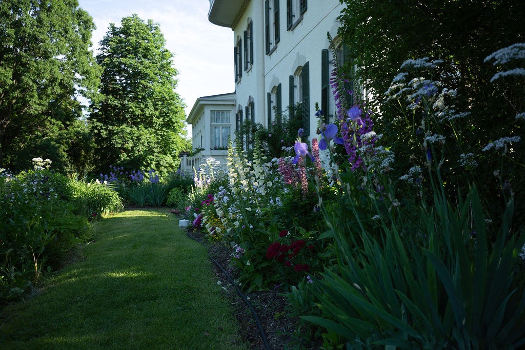 A white house with a garden in front.