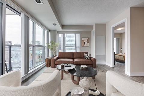 A living room with a brown couch and white chairs.
