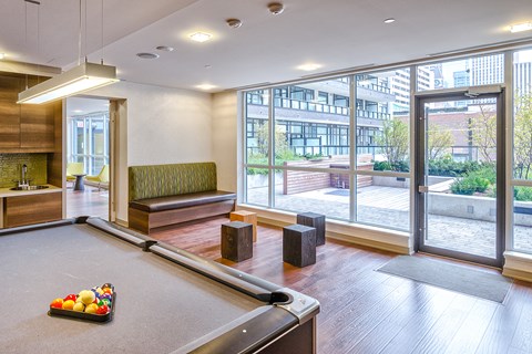 A pool table with a tray of balls on it in a room with a view of the city.
