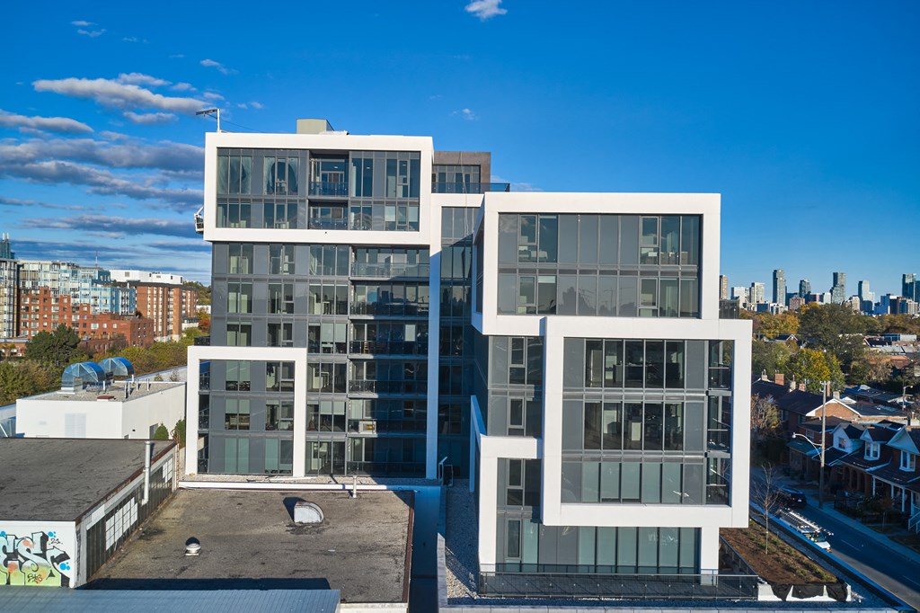 A modern building with glass windows and a flat roof is surrounded by other buildings.
