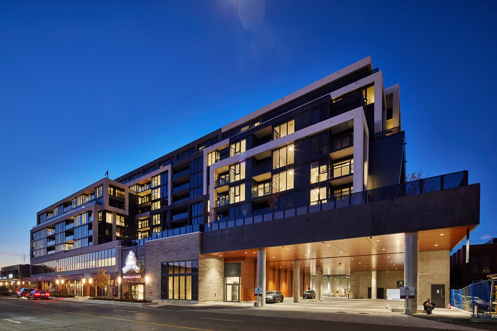 A modern building with a large glass facade and a lit-up Christmas tree in the lobby.