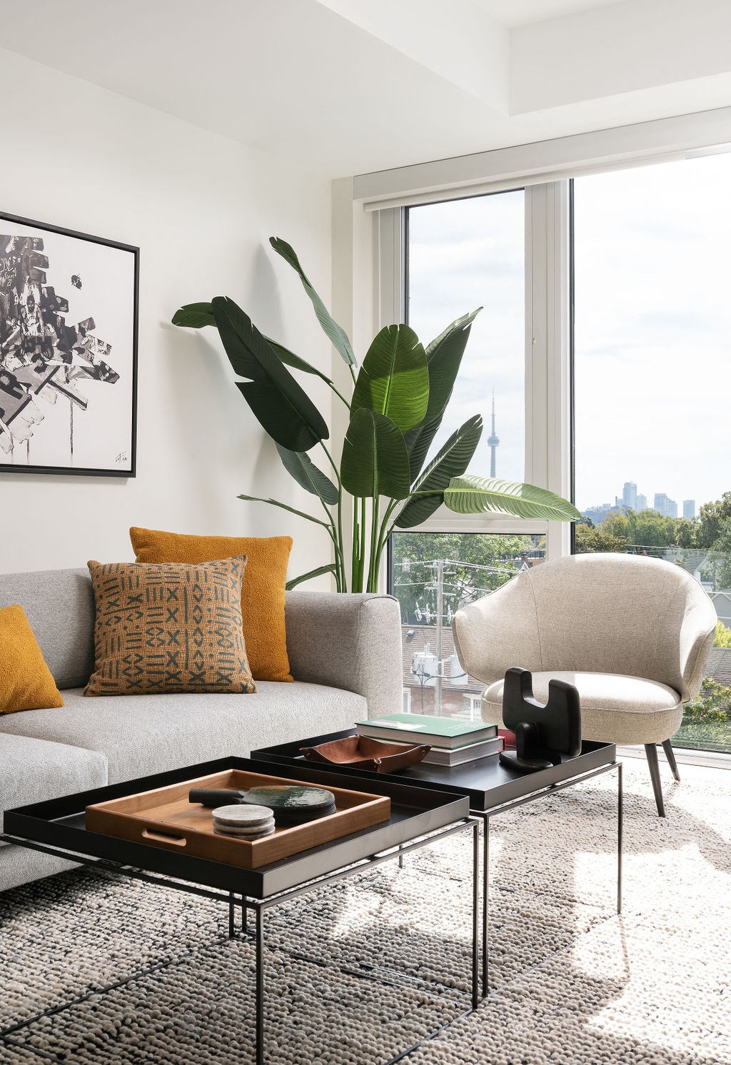 A living room with a grey couch, a coffee table, and a large window.