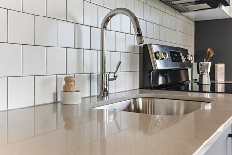A kitchen with a sink and a black stove.