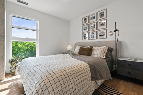 A bedroom with a large bed and a window overlooking a green landscape.