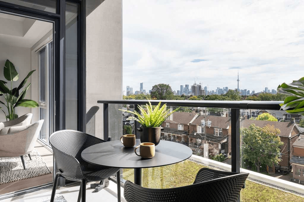 A balcony with a table and chairs overlooking a city skyline.