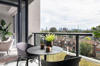 A balcony with a table and chairs overlooking a city skyline.