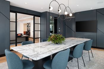 A modern dining room with a marble table and blue chairs.