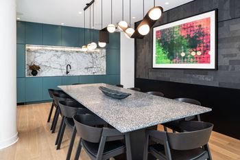 A modern dining room with a marble backsplash and a large painting on the wall.