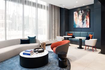 A modern living room with a large window and a painting on the wall.