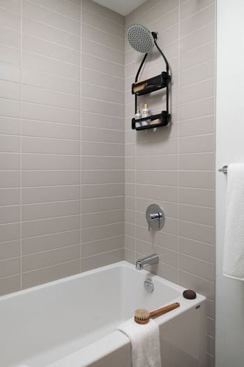 A white bathtub with a shower head and a towel hanging on the side.