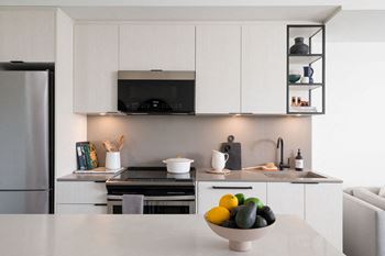 A modern kitchen with a bowl of fruit on the counter.