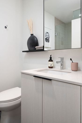 A bathroom with a toilet, sink, and a mirror.
