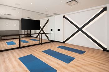 A yoga studio with blue mats and a black screen.