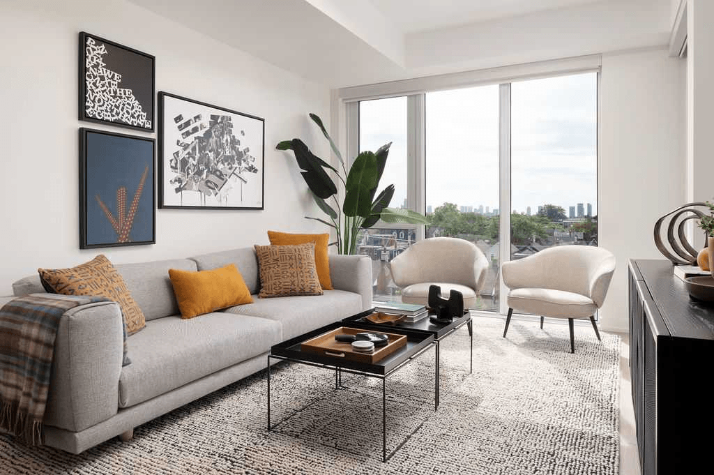 A living room with a grey couch, a coffee table, and a large window.