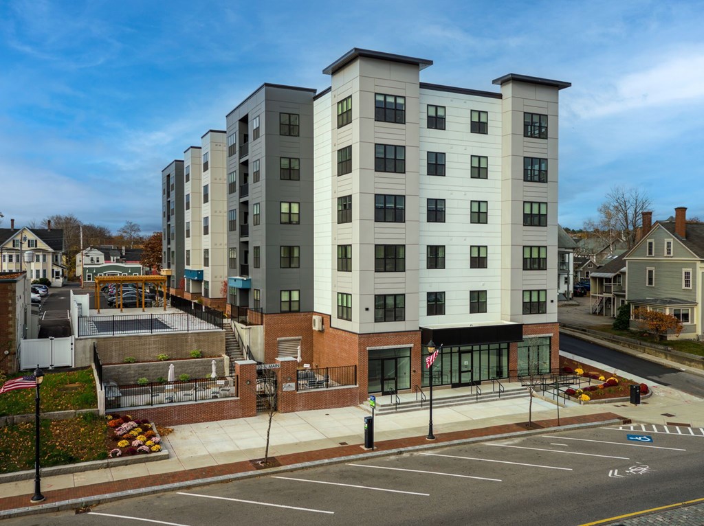 A modern apartment building with a parking lot in front.