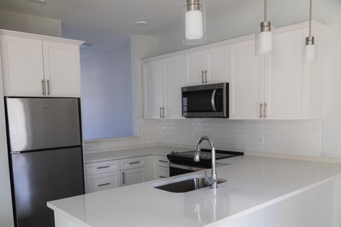A kitchen with white cabinets and a black fridge.