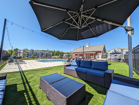 a backyard with a pool and lounge furniture and an umbrella