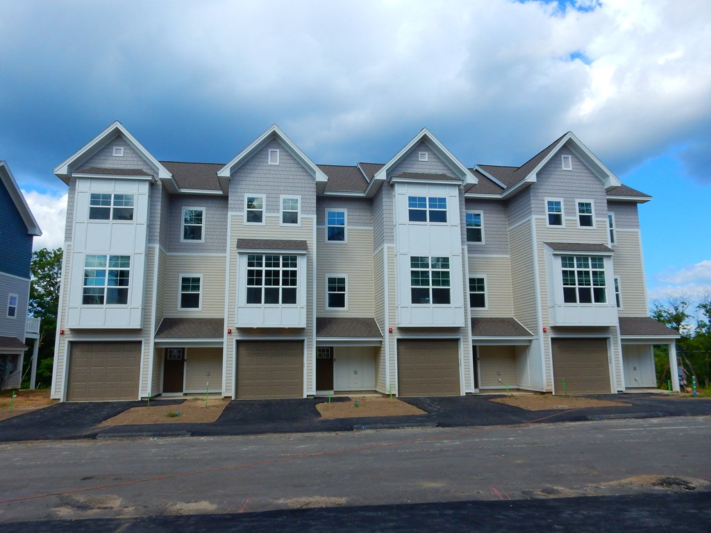 a row of apartment buildings with white siding and gray roofs