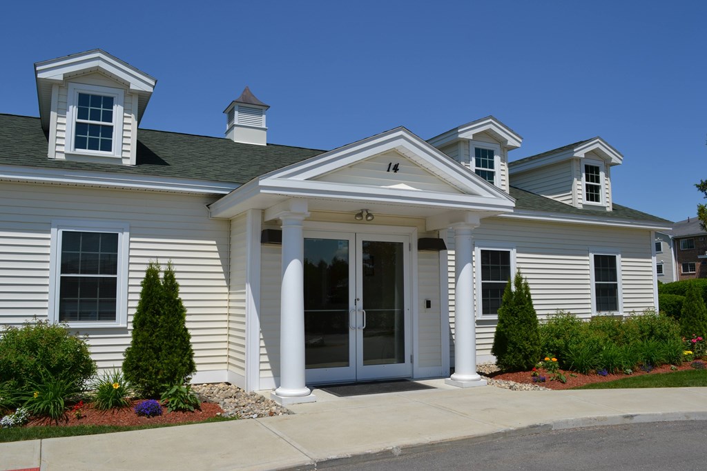 A white house with a black roof and a porch.