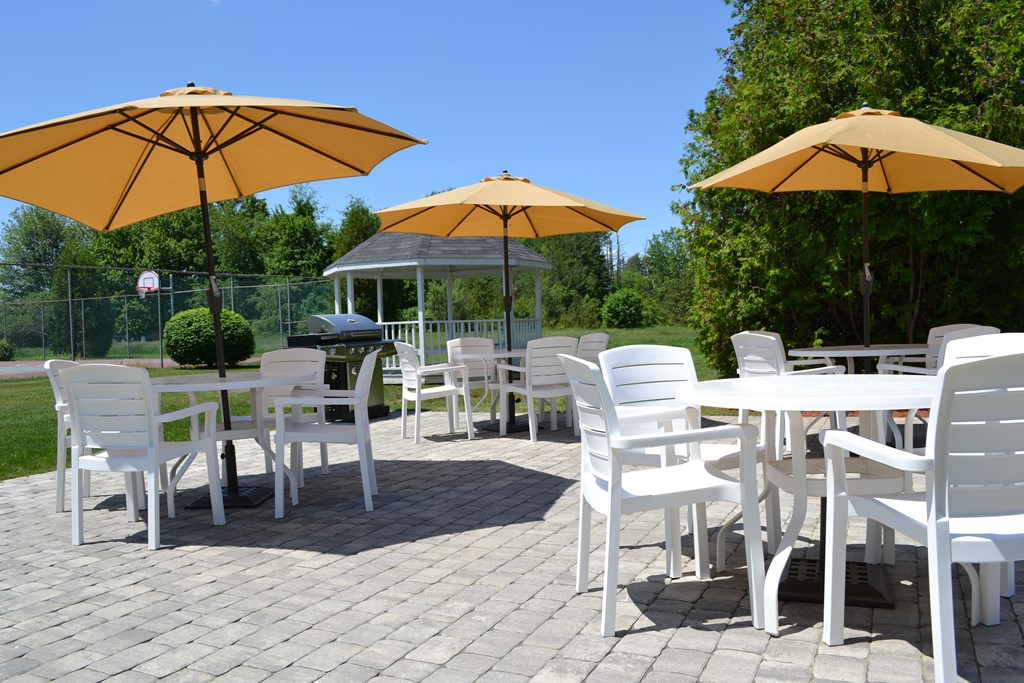 A patio with white chairs and yellow umbrellas.